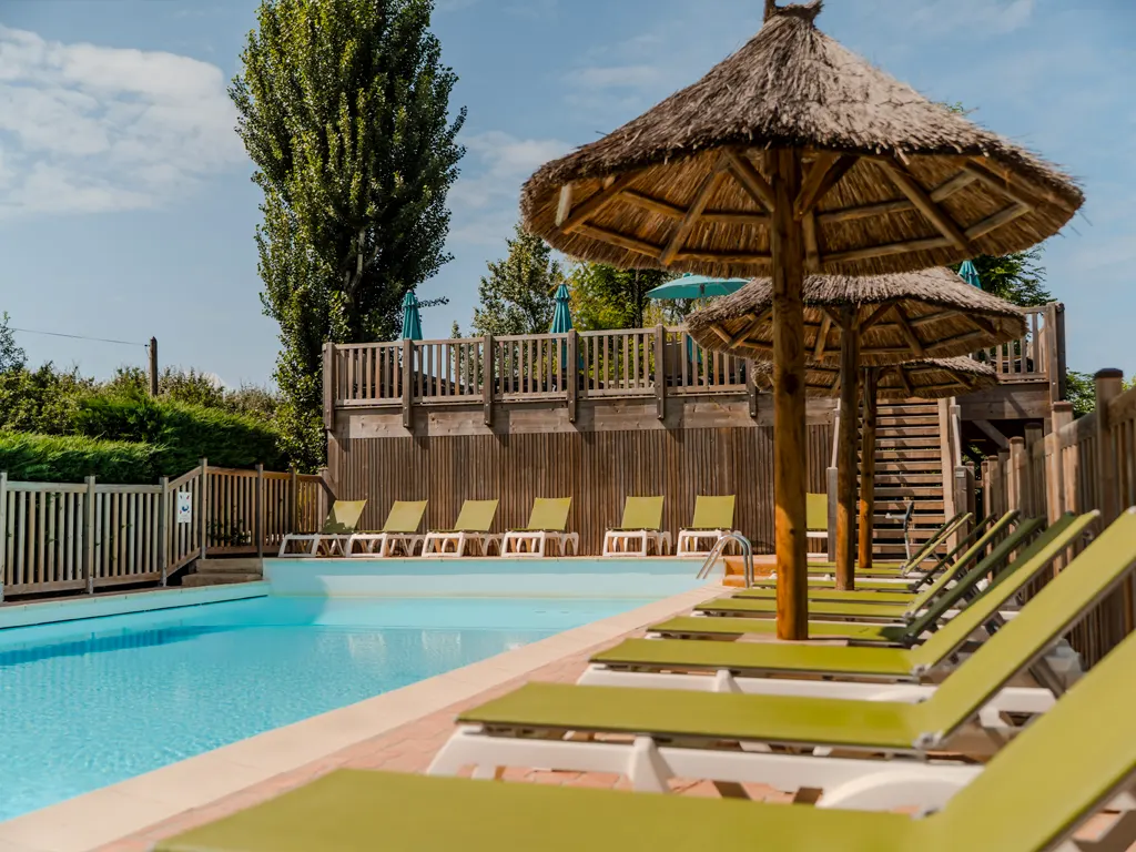 Transats, parasols et paillotes au bord de la piscine